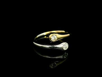 18K white and yellow gold bypass ring with two round diamonds in bezel settings at the ends of curved, overlapping bands.