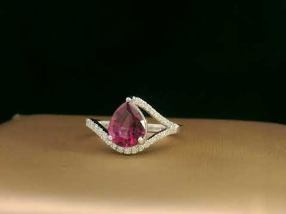 18K white gold rhodolite garnet and diamond wave ring featuring a 1.97ct pear-cut garnet framed by 0.23ct pavé diamonds in an elegant wave design.