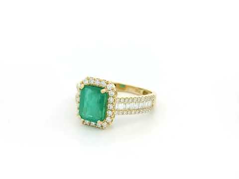 18K yellow gold emerald and diamond halo ring with baguette diamond accents by Emirates Diamonds.