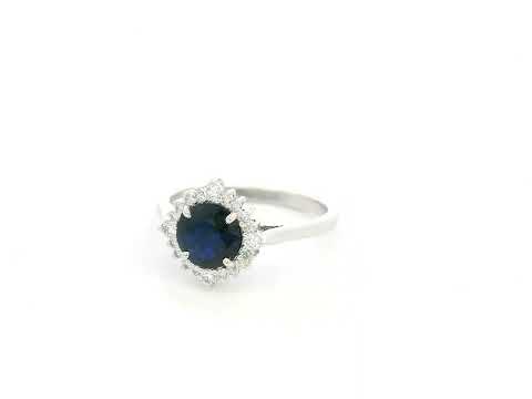 Blue sapphire and diamond halo ring in 18K white gold featuring a 1.24 carat natural blue sapphire and 0.18 carat diamonds