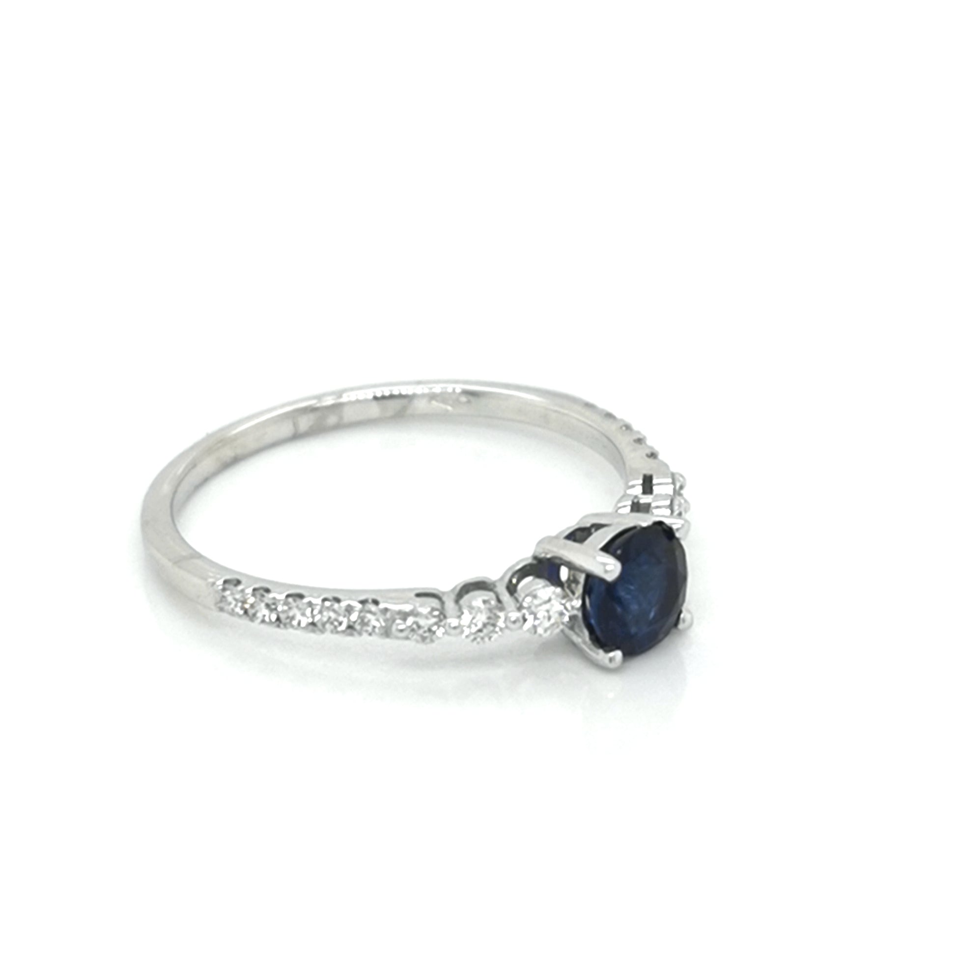 Traditionally Diamonds Are Most Prefered Choice For Engagement Rings. Gemstone Rings Are A Trendy Alternative. Both Diamonds And Sapphires Are Rare And Precious, But The Combination Of Both Not Only Reduces The Cost But Also Make A Gorgeous Ring That Truly Stands Out.  This Marvelous Ring Features A Solitaire Deep Blue Round Cut Sapphire secured In Four Prog, Round Cut Brilliant Diamonds Graduates Flowing Down The Shank Half Way. Eye Catching Design Is Sure To Draw Many Compliments.