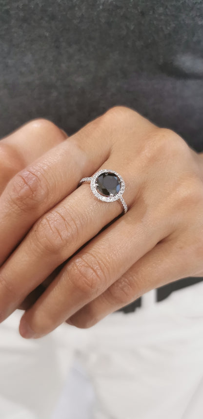 Solitaire Black Diamond Ring With A Diamond Halo In 18k White Gold.