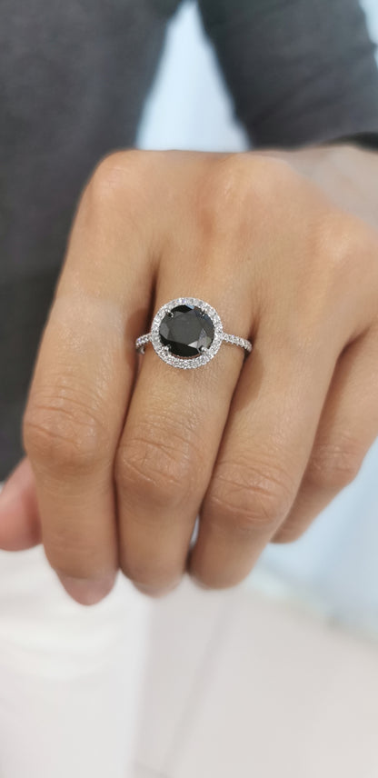 Solitaire Black Diamond Ring With A Diamond Halo In 18k White Gold.